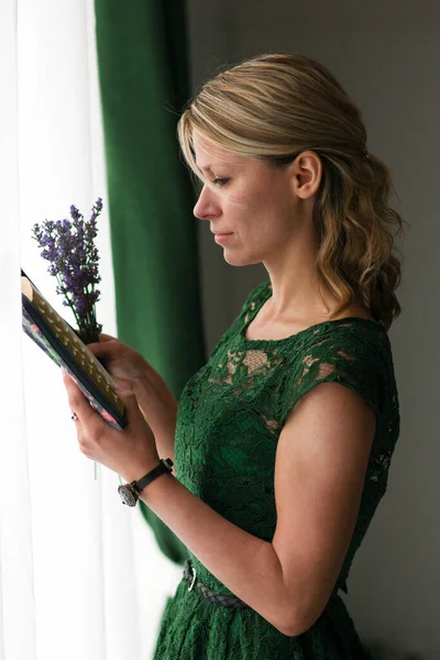 穿着老式绿色衣服的女人在窗边看书 — 图库照片