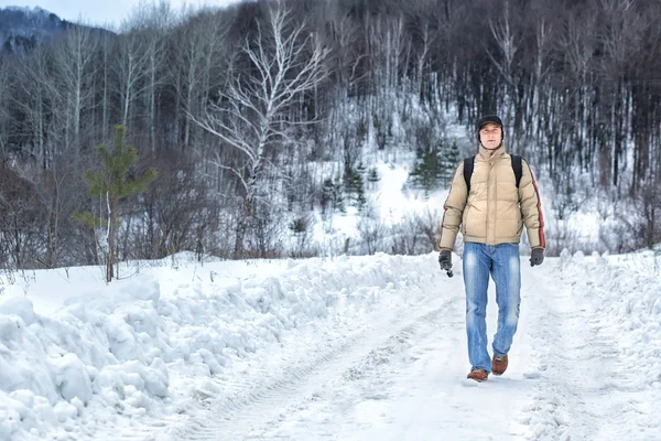 Homem caminha ao longo de uma estrada nevada — Fotografia de Stock