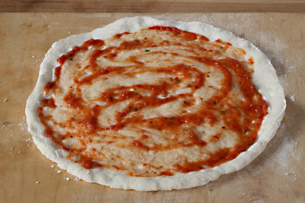 raw pizza with sauce and red pepper, closeup