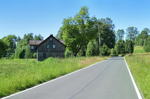 Дорога и старый деревянный дом — стоковое фото