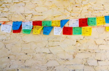 Buddhist tibetan prayer flags against wall clipart