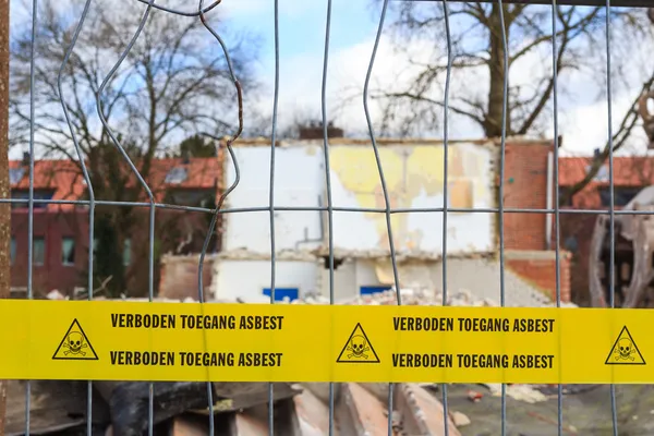 Yellow tape with Dutch text 'no trespassing asbestos' — Stok fotoğraf