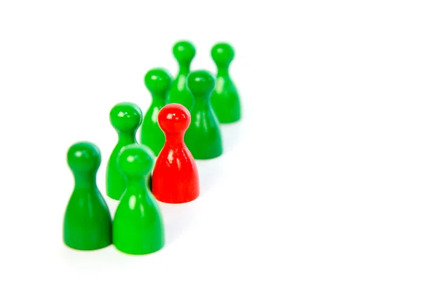 Red pawn in a line-up of green pawns — Stock Photo, Image