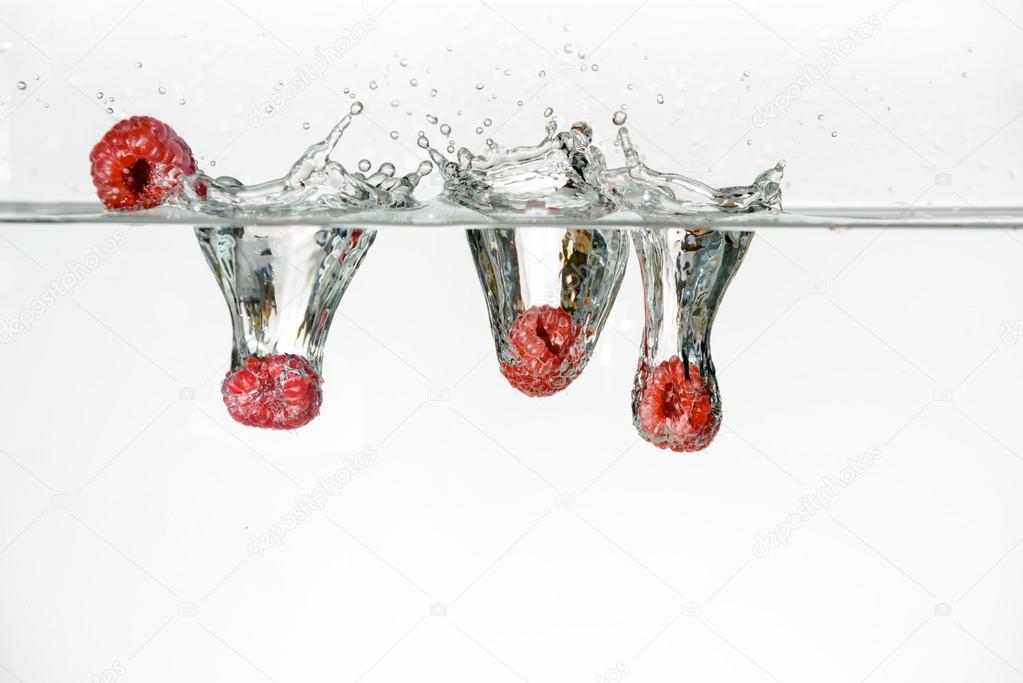 Raspberries falling into water