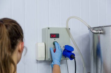 Endüstride çalışan kadın, tank termostatını ayarlıyor