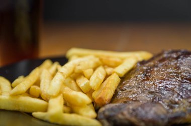 Patates kızartması ve bir bardak birayla nefis ızgara entrecote tabağı.