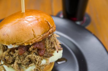 Ahşap masa ve siyah arka planda lezzetli ev yapımı domuz burger.