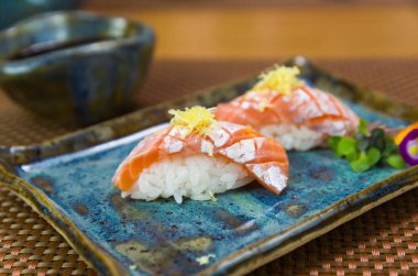 İki zarif nigiri sushi (nigirzushi) tabağı. Elmas biçimli bıçak kesikleri ve limon lezzetiyle süslenmiş..