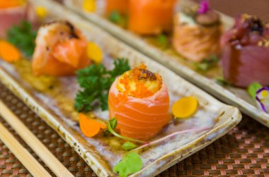 Farklı çeşnilerle süslenmiş zarif suşi tabağı. Seçici odak.