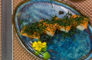 Farklı aromalı uramaki suşisi ile süslenmiş bir tabak. Seçici odak.