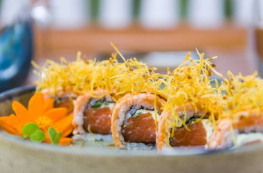 Farklı aromalı uramaki suşisi ile süslenmiş bir tabak. Seçici odak.