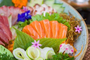 Farklı aromalı Sashimi suşisi, somon balığı, ton balığı, halibut ve yanmış somon ile süslenmiş bir tabak. Seçici odak.