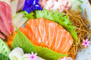 Farklı aromalı Sashimi suşisi, somon balığı, ton balığı, halibut ve yanmış somon ile süslenmiş bir tabak. Seçici odak.