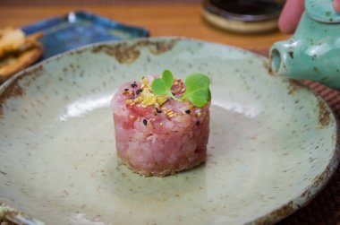 Süslü bir tabakta ton balıklı tartar lezzetine soya sosu döken adam..