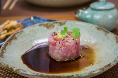 Süslü bir tabakta ton balıklı tartar lezzetine soya sosu döken adam..