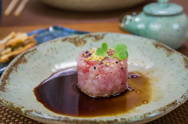 Süslü bir tabakta ton balıklı tartar lezzetine soya sosu döken adam..