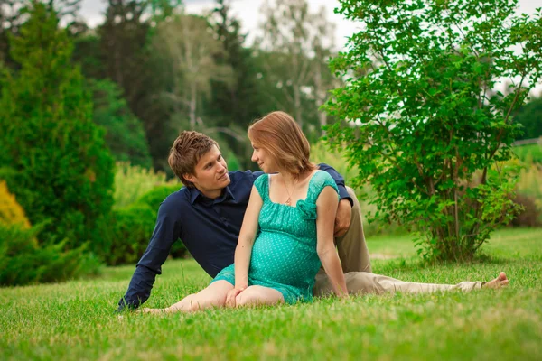 Young pregnant woman with young man in the park — Stock Photo, Image