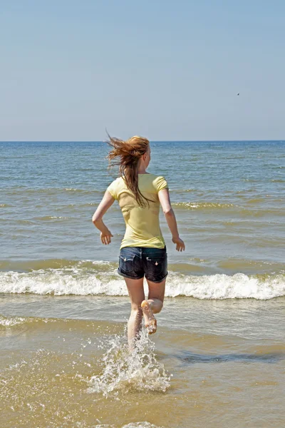 Young blonde woman running into the water — Stock Photo, Image