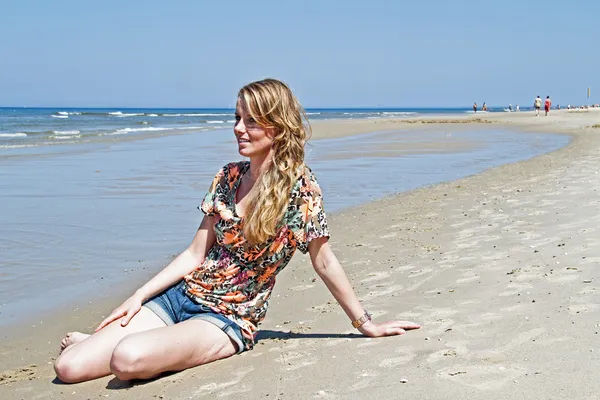 Mujer rubia joven sentada en el paseo marítimo desde el mar del norte — Foto de Stock
