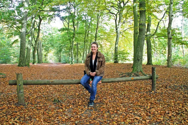 Зріла жінка сидить на лавці в лісі — стокове фото