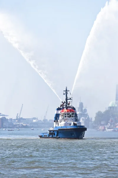 Blue fire boat on harbor spraying bright streams of water in d — Stock Photo, Image