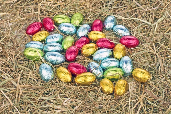 Маленькие цветные яйца в соломе — стоковое фото