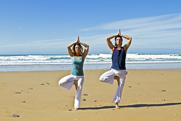 Casal fazendo excersises de ioga na praia — Fotografia de Stock