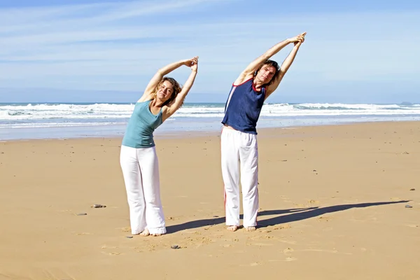Pareja haciendo ejercicios de yoga en la playa —  Fotos de Stock