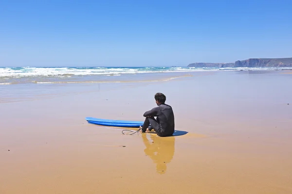 Серфер на пляже, наблюдающий за волнами — стоковое фото
