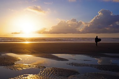 gün batımında sahilde gezinen