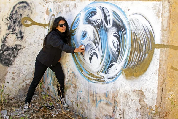 Mujer en rociado negro en una pared de ladrillo de graffiti — Foto de Stock