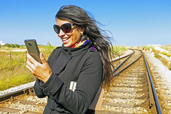 Junge schöne Frau liest eine SMS auf einer Eisenbahn — Stockfoto