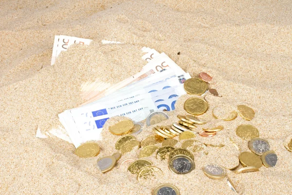 Bank banknotów i monet w piasku — Zdjęcie stockowe