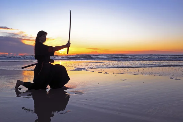 Young samurai women with Japanese sword(Katana) at sunset on the — Stock Photo, Image