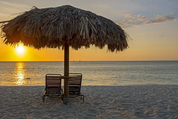 カリブ海のアルバ島のビーチで日没時に傘を投げる — ストック写真