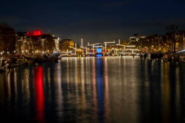 Geceleyin Hollanda 'daki Amstel' de aydınlatılmış Minik Köprü ile Amsterdam