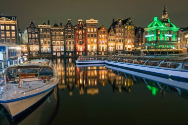 Hollanda 'daki Damrak' ta geceleri geleneksel evler ve tekne gezileri.