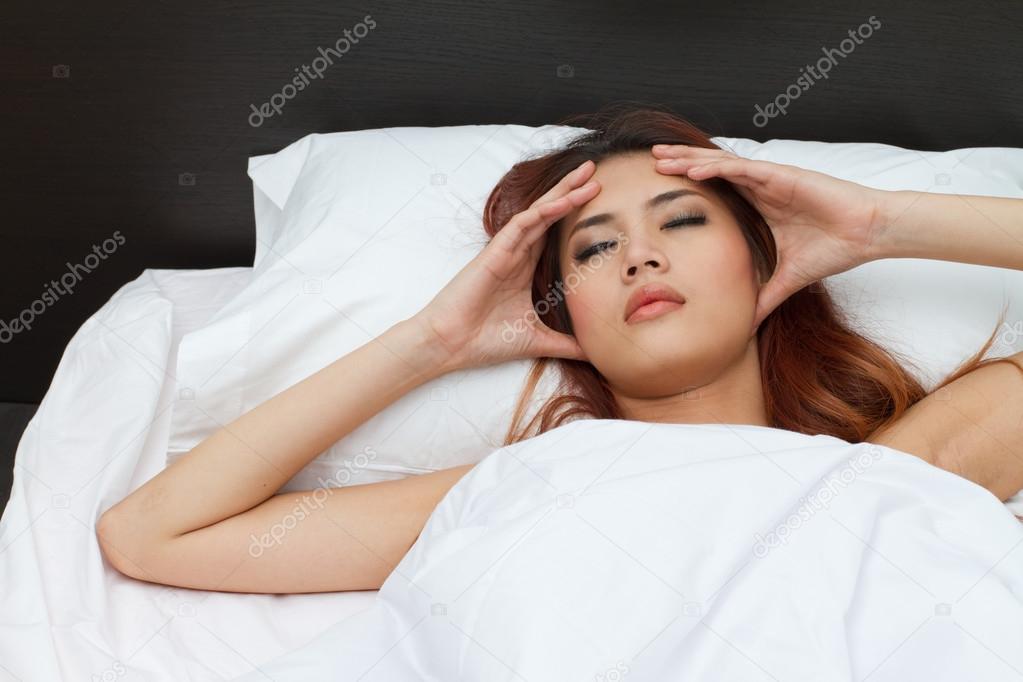 sick woman on bed, massaging her head