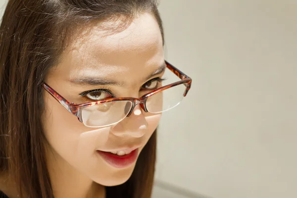 Beautiful woman look through her eyeglasses on plain background — Stock Photo, Image
