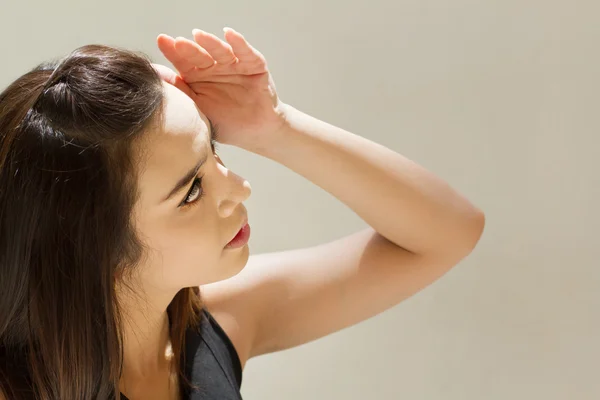 Mujer sufre de calor de luz solar fuerte, fondo liso — Foto de Stock