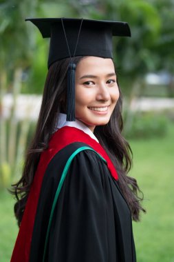 Mezuniyet gününde gülümseyen mutlu üniversite öğrencisi, başarılı eğitim kavramı, mutlu mezuniyet, kadın eğitim eşitliği, yurtdışında eğitim, yüksek öğretim diploması, denizaşırı eğitim bursu