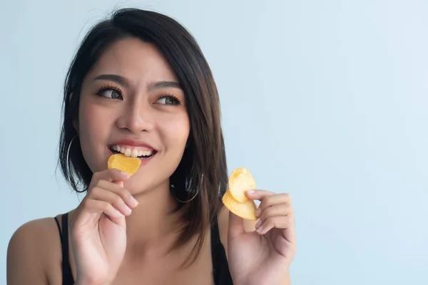 Woman eating potato chips or crispy fried potato, health and medical concept of unhealthy food, high sodium and saturated fat fried food, unhealthy lifestyle, bad breath, oral care