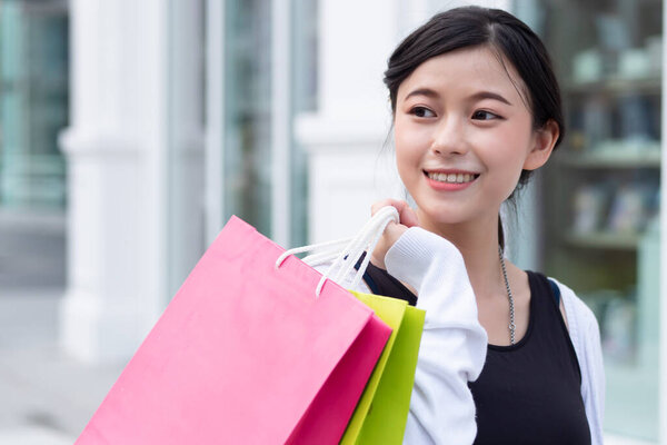 Happy woman shopping in neighborhood shopping mall looking to blank space