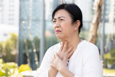 Hasta alerjik yaşlı kadın soğuk algınlığı, grip veya koronavirüs enfeksiyonu, COVID-19 semptomu yüzünden boğaz ağrısı çekiyor.