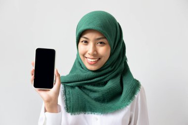 Gülümseyen Müslüman kadın siyah akıllı telefon ekranı gösteriyor