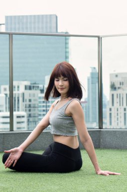 Yoga yapan kadın şehir ortamında vücut bükme hareketi yapıyor. İç sindirim organı yararına karın pozu veriyor.