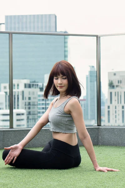 Yoga yapan kadın şehir ortamında vücut bükme hareketi yapıyor. İç sindirim organı yararına karın pozu veriyor.