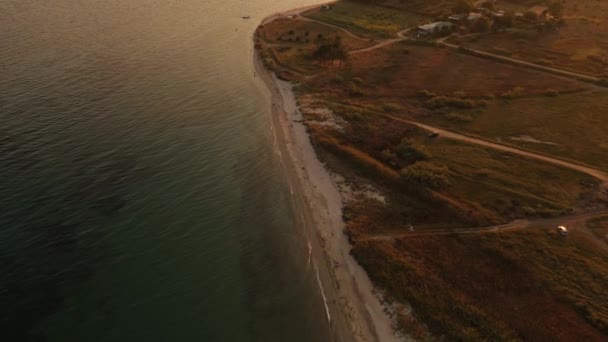 Vista aérea superior de 4k sobre el mar de playa de arena puesta del sol. Grecia pueblo costero pequeñas casas bahía mar tracio — Vídeos de Stock