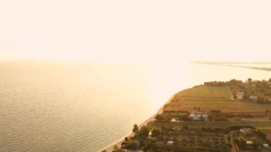 Gün batımı kum sahil denizi üzerindeki 4K hava manzarası. Yunanistan sahil köyü Trakya körfezi küçük evleri 