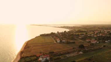 Gün batımı kum sahil denizi üzerindeki 4K hava manzarası. Yunanistan sahil köyü Trakya körfezi küçük evleri 